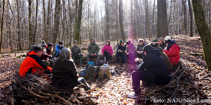Die Teilnehmenden sitzen im Kreis im winterlichen Wald